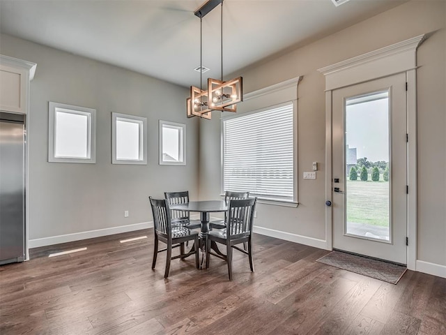 dining room featuring a healthy amount of sunlight, dark wood-type flooring, and an inviting chandelier