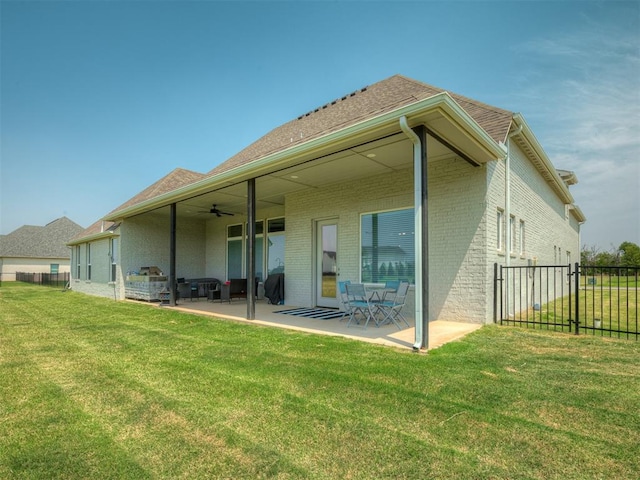 rear view of property with ceiling fan, a yard, and a patio area