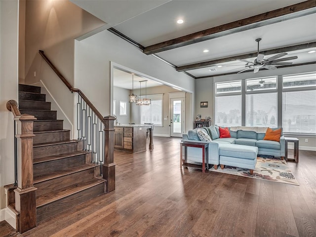 living room with beam ceiling, ceiling fan with notable chandelier, and dark wood-type flooring