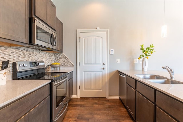 kitchen featuring hanging light fixtures, sink, dark hardwood / wood-style floors, decorative backsplash, and appliances with stainless steel finishes