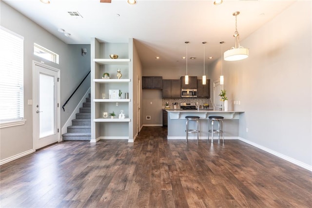 kitchen with dark brown cabinets, a kitchen breakfast bar, dark wood-type flooring, and decorative light fixtures