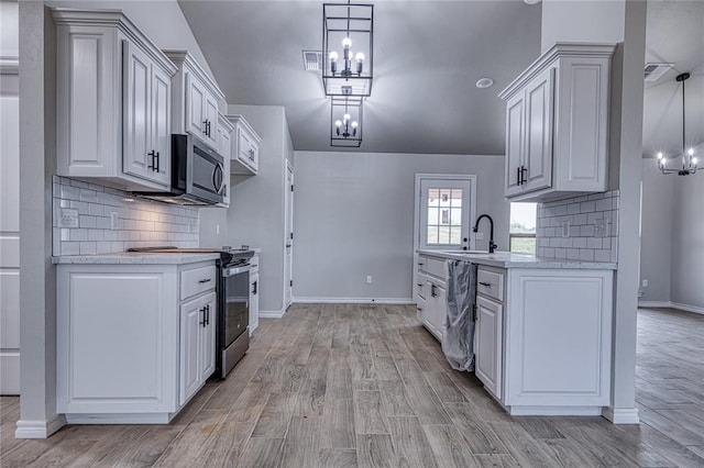 kitchen featuring white cabinets, appliances with stainless steel finishes, light hardwood / wood-style flooring, and pendant lighting