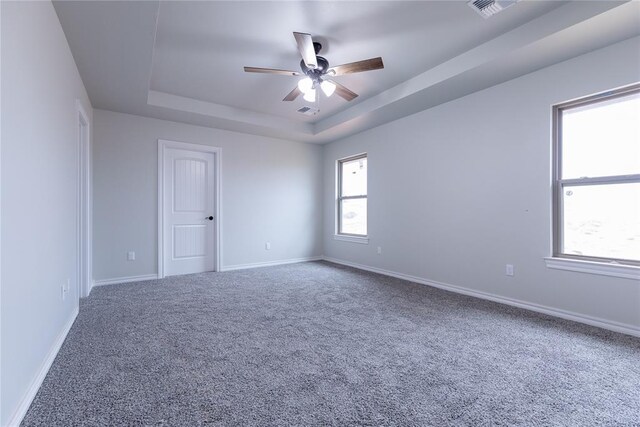 carpeted empty room with a raised ceiling and ceiling fan