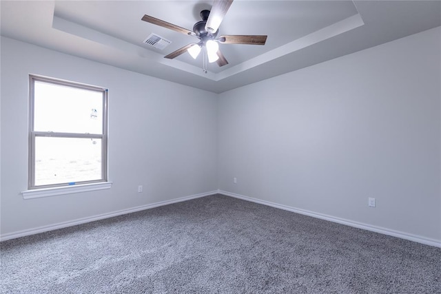 unfurnished room featuring carpet flooring, a tray ceiling, and ceiling fan