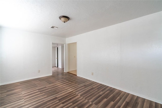 spare room featuring a textured ceiling and dark wood-type flooring