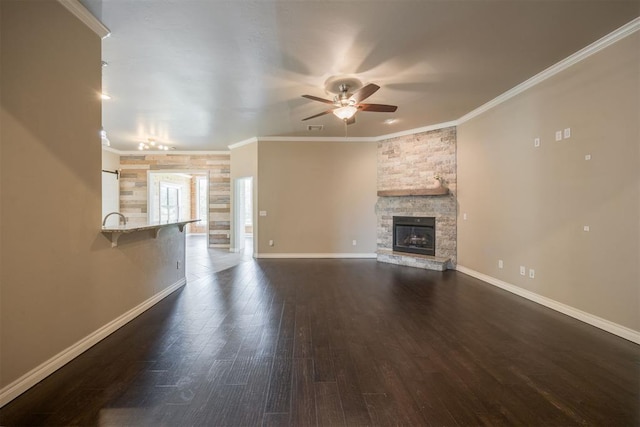 unfurnished living room with dark hardwood / wood-style flooring, a stone fireplace, ceiling fan, and ornamental molding