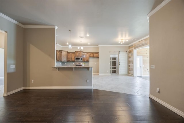 unfurnished living room with dark hardwood / wood-style flooring, a barn door, and ornamental molding