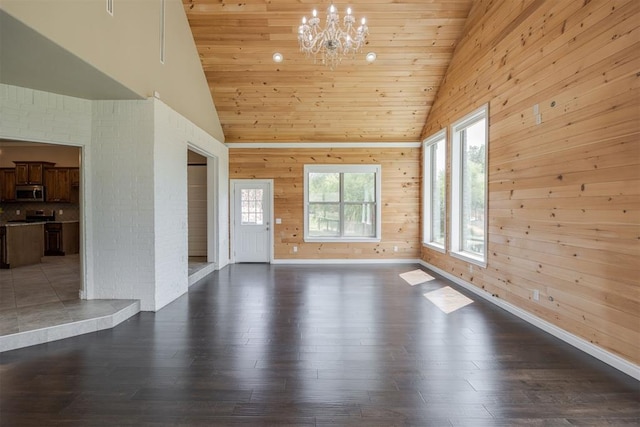 unfurnished living room with dark wood-type flooring, high vaulted ceiling, a chandelier, wooden walls, and wood ceiling