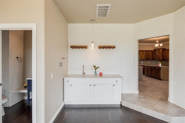 bar featuring pendant lighting, decorative backsplash, white cabinets, and wood-type flooring