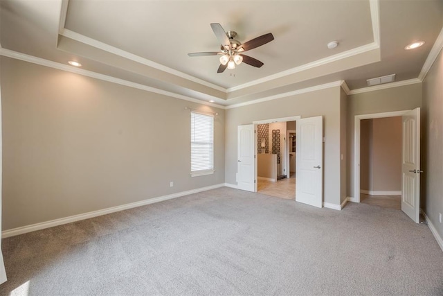 unfurnished bedroom with ceiling fan, a raised ceiling, light colored carpet, and ornamental molding