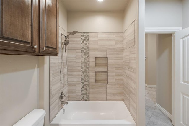 bathroom with toilet, tile patterned floors, and tiled shower / bath