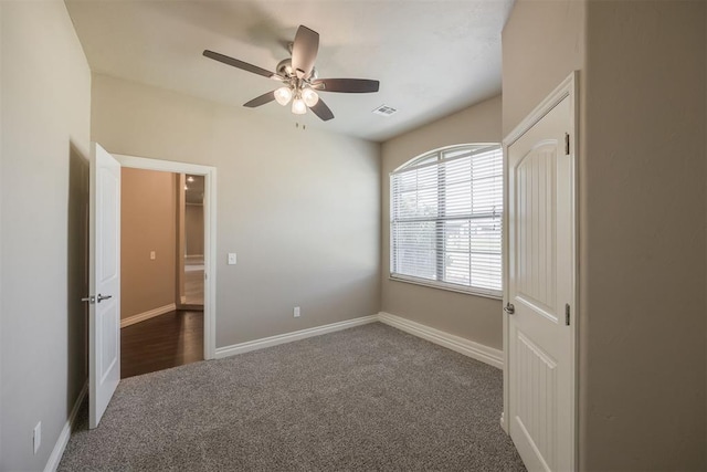 unfurnished bedroom with dark carpet and ceiling fan