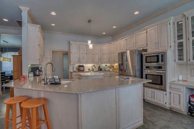 kitchen with sink, hanging light fixtures, a kitchen breakfast bar, appliances with stainless steel finishes, and ornamental molding