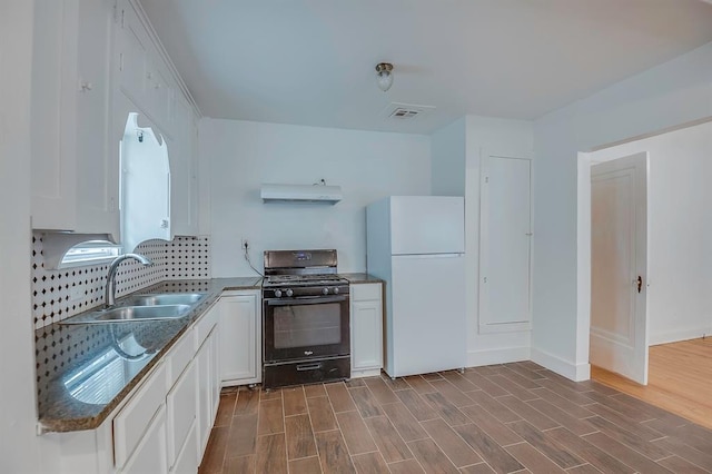 kitchen featuring dark hardwood / wood-style flooring, black gas range oven, sink, white cabinets, and white fridge