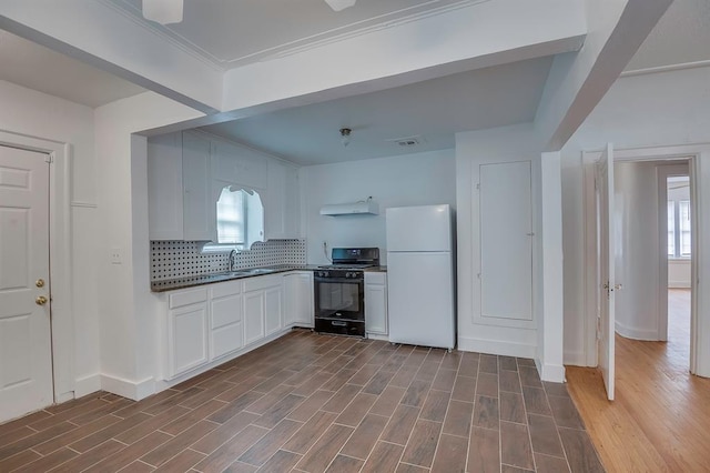 kitchen featuring plenty of natural light, white fridge, dark wood-type flooring, and black range with gas cooktop