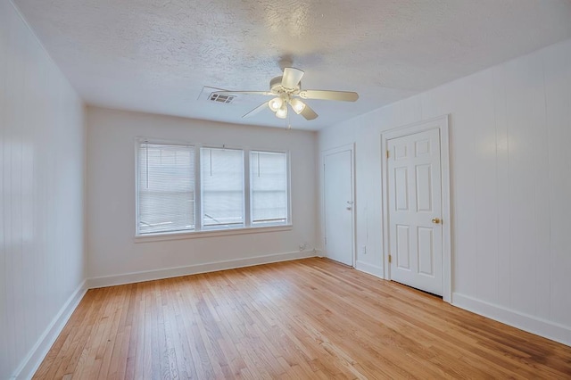 spare room with a textured ceiling, light hardwood / wood-style flooring, and ceiling fan