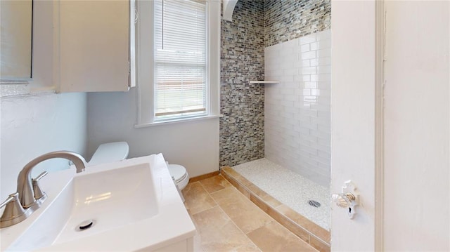 bathroom with tiled shower, sink, and toilet