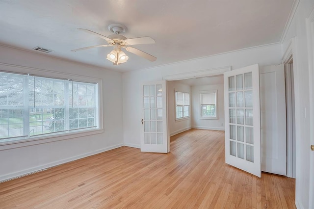 empty room with french doors, light wood-type flooring, and ornamental molding