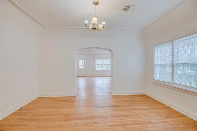 spare room featuring an inviting chandelier and light wood-type flooring