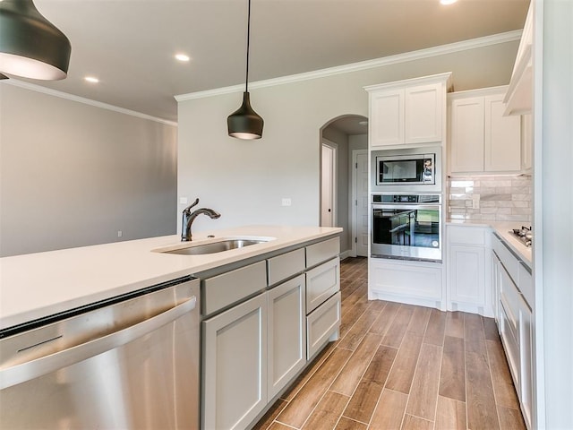 kitchen featuring white cabinetry, sink, light hardwood / wood-style flooring, pendant lighting, and appliances with stainless steel finishes