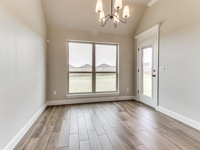 unfurnished dining area with a healthy amount of sunlight, light wood-type flooring, lofted ceiling, and a notable chandelier