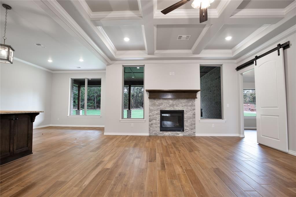 unfurnished living room with plenty of natural light, a barn door, and light hardwood / wood-style flooring