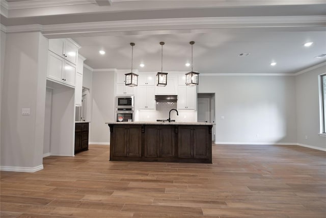 kitchen with pendant lighting, a center island with sink, crown molding, light hardwood / wood-style flooring, and stainless steel appliances