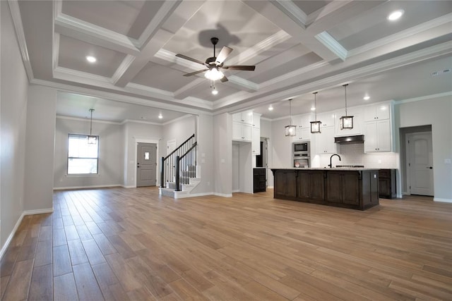 kitchen with white cabinetry, an island with sink, light hardwood / wood-style floors, and ornamental molding