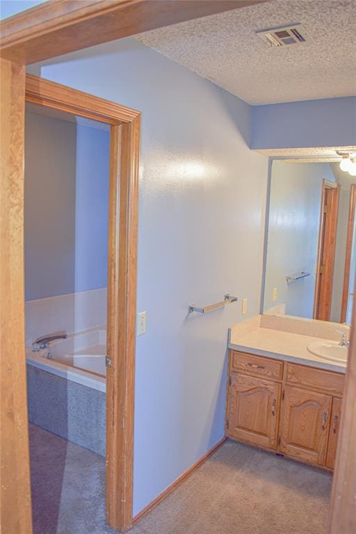 bathroom with a relaxing tiled tub, a textured ceiling, and vanity