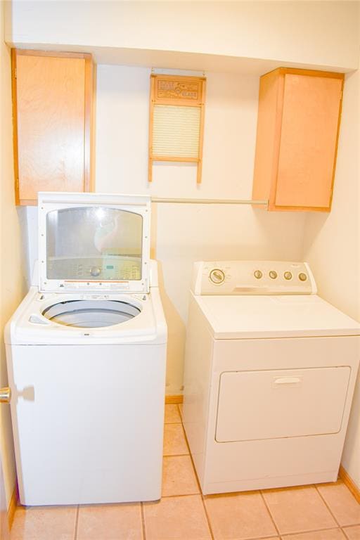 clothes washing area with washer and clothes dryer, light tile patterned flooring, and cabinets