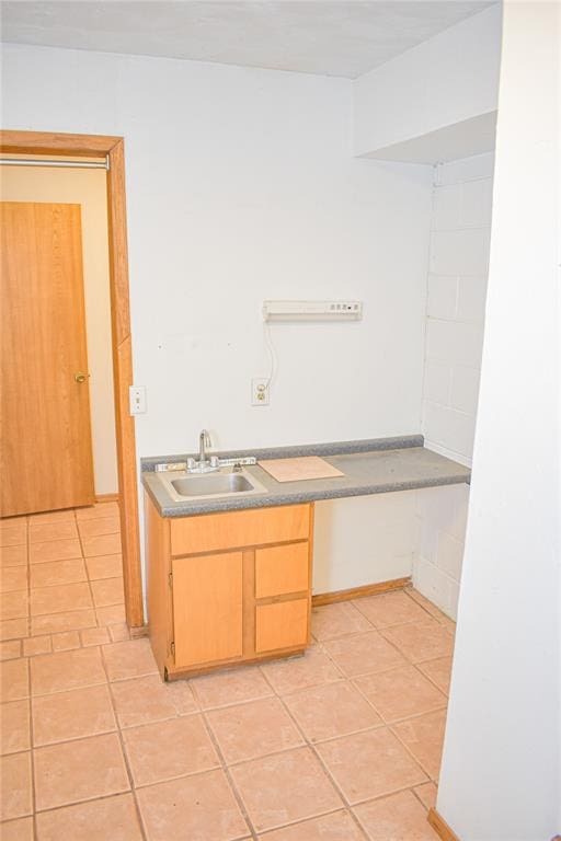 interior space with light brown cabinets, light tile patterned floors, and sink