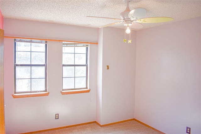 empty room with light carpet, plenty of natural light, and a textured ceiling