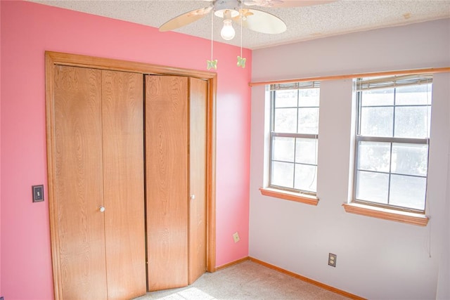 unfurnished bedroom with light carpet, a textured ceiling, a closet, and ceiling fan