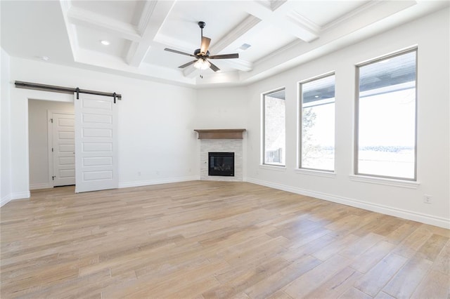 unfurnished living room featuring light wood finished floors, a barn door, baseboards, and a ceiling fan