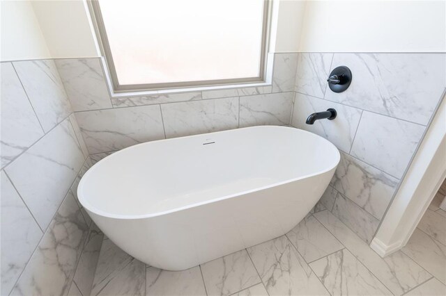 bathroom with a freestanding bath and marble finish floor