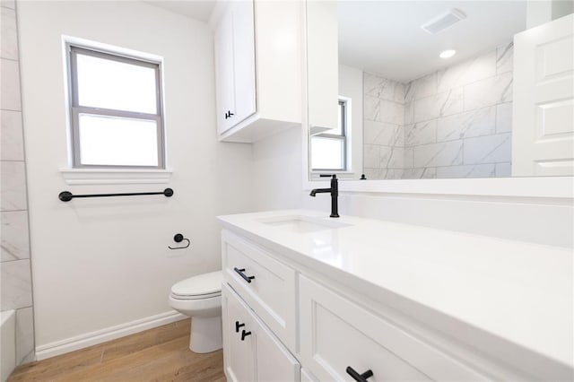 full bath with visible vents, toilet, vanity, wood finished floors, and baseboards