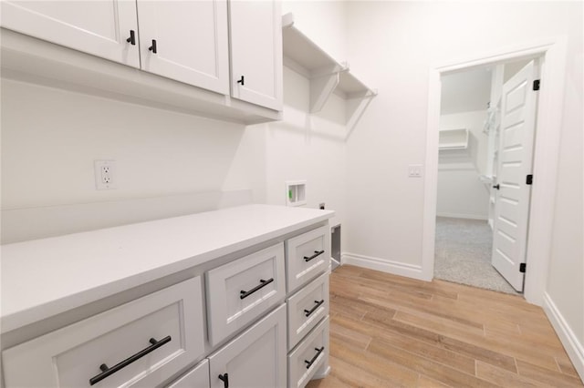 interior space featuring light countertops, light wood-style flooring, baseboards, and white cabinetry