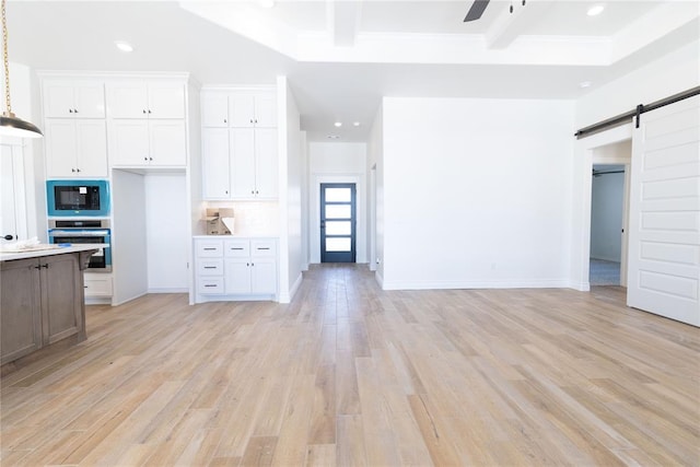 kitchen with built in microwave, white cabinets, stainless steel oven, and a barn door