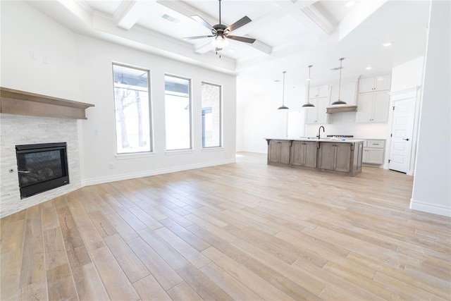 unfurnished living room with light wood-type flooring, baseboards, a fireplace, and visible vents