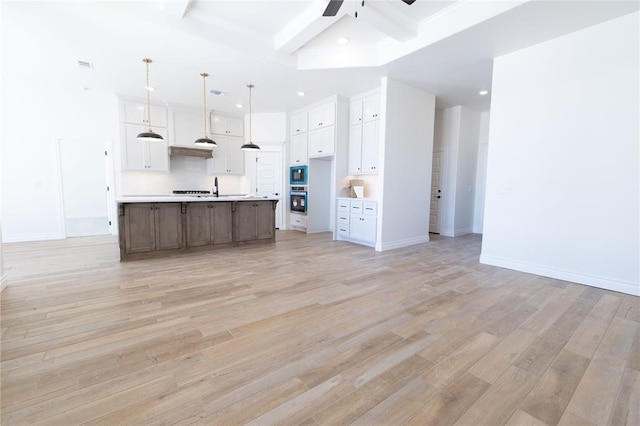 kitchen featuring a large island, light countertops, hanging light fixtures, white cabinetry, and stainless steel oven