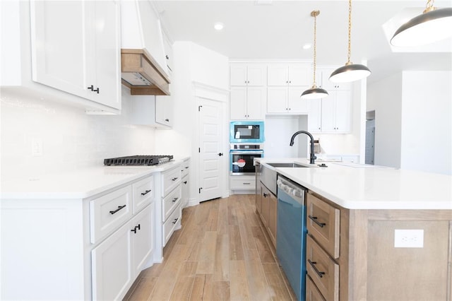 kitchen featuring stainless steel appliances, a kitchen island with sink, white cabinetry, and light countertops