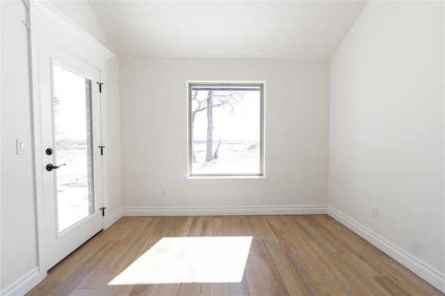 spare room with baseboards, plenty of natural light, and light wood-style floors