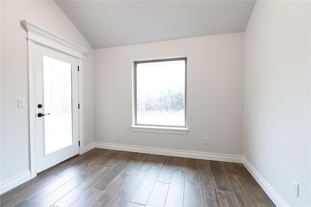 empty room featuring lofted ceiling, dark hardwood / wood-style floors, and a wealth of natural light