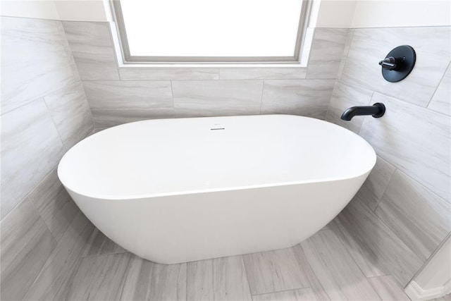 bathroom with tile walls and a tub to relax in