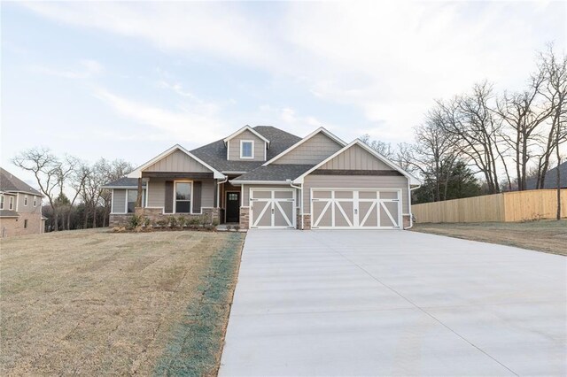 craftsman-style house with concrete driveway, stone siding, an attached garage, a front yard, and fence
