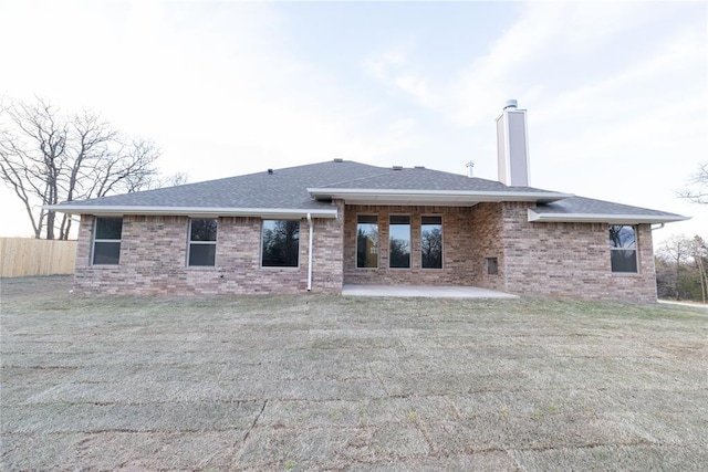 back of house with a patio area, brick siding, a chimney, and a shingled roof