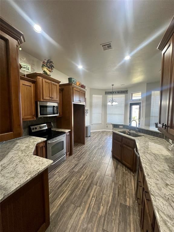 kitchen featuring stainless steel appliances, dark wood-type flooring, sink, a notable chandelier, and hanging light fixtures