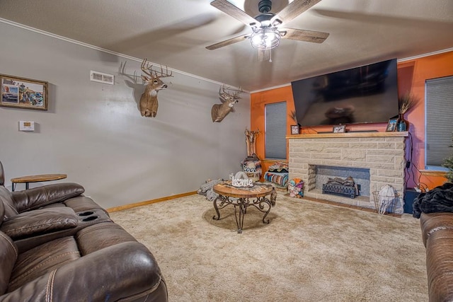 carpeted living room with ornamental molding, ceiling fan, and a stone fireplace