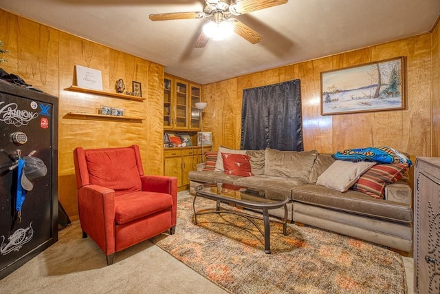 living room with wooden walls, ceiling fan, and carpet