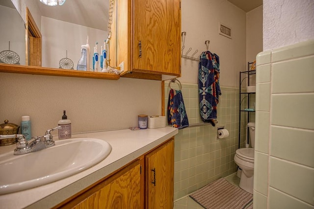 bathroom with tile walls, toilet, tile patterned floors, and vanity